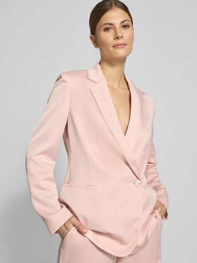 Frauenmodel trägt Relaxed Fit Blazer mit Reverskragen von Jake*s Collection in zartem Rosa, Paspeltaschen, Knopfverschluss, Nahaufnahme Oberkörper.