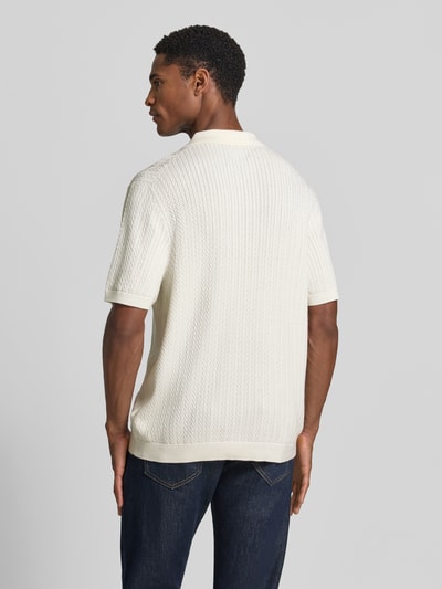 Męski model nosi Regular Fit Poloshirt mit Strukturmuster von Christian Berg Men, ecru, kołnierzyk polo, listwa guzikowa, długość tyłu 72 cm, długość rękawów 25 cm, fakturowany wzór, Ganzkörperansicht Rückansicht.