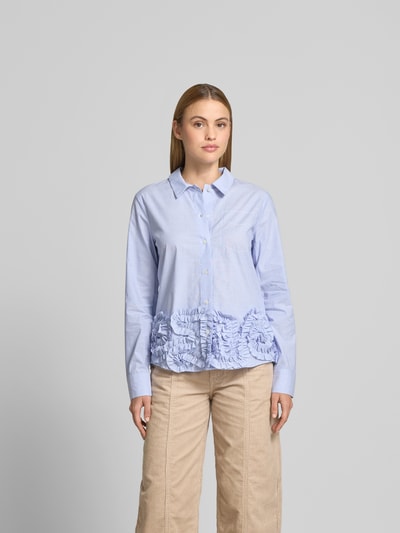 Frauenmodel trägt Regular Fit Hemdbluse mit Rüschenbesatz von BAUM & PFERDGARTEN aus reiner Baumwolle, hellblau, Ganzkörperansicht von vorne.