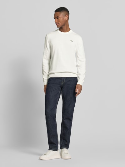 Männermodel trägt Regular Fit Strickpullover aus Baumwoll-Mix von Lacoste, Optik: Unifarben, Logo-Stitching, Ganzkörperansicht von vorne.