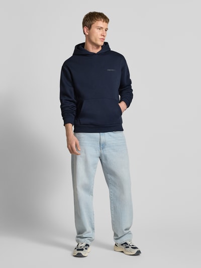 Männermodel trägt Regular Fit Hoodie mit Logo-Print von Review in Dunkelblau, Baumwoll-Mix, Kängurutasche, Ganzkörperansicht von vorne