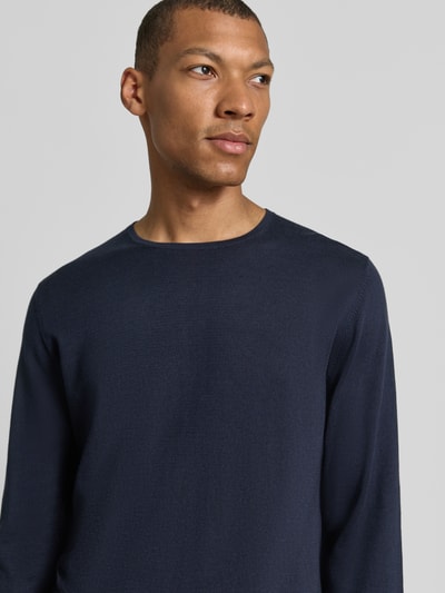 Männermodel trägt Strickpullover aus Baumwolle mit Rundhalsausschnitt von Christian Berg Men in Dunkelblau, Nahaufnahme Oberkörper. Slim Fit, glatte Struktur.