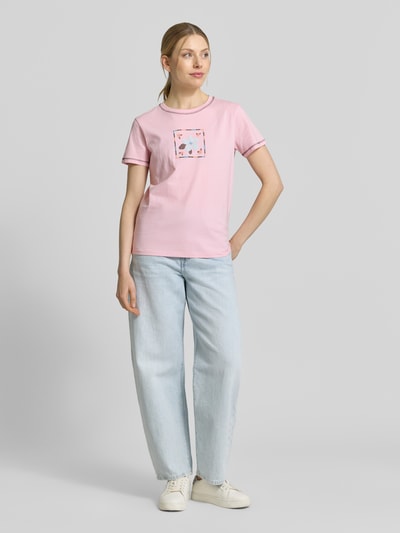 Frauenmodel trägt T-Shirt mit Motiv und Rundhalsausschnitt von Jake*s Casual in Rosa, Regular Fit, reine Baumwolle, kombiniert mit hellblauer Jeans, Ganzkörperansicht von vorne.