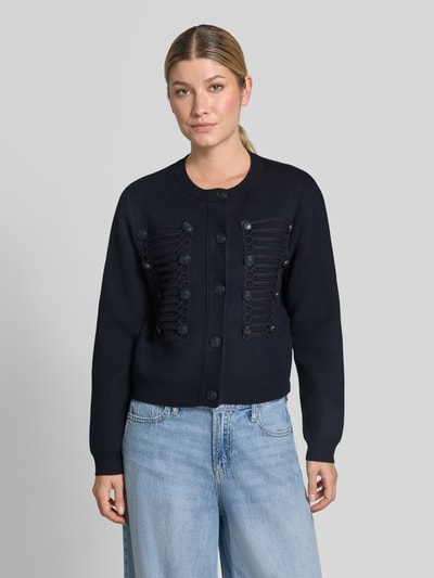 Frauenmodel trägt Cardigan aus Viskose-Mix mit Zierknöpfen Modell 'GENIO' von MANGO, regular Fit, Rundhalsausschnitt, Ganzkörperansicht von vorne.