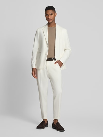 Männermodel trägt Slim Fit Stoffhose mit Bundfalten Modell 'Chasy' von Drykorn aus Baumwoll-Mix, Eingrifftaschen, Ganzkörperansicht von vorne.