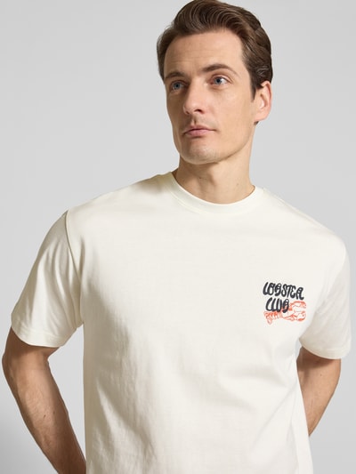 Männermodel trägt T-Shirt aus Baumwolle Modell 'PETER' von MCNEAL, gerade geschnitten, cremeweiß, dezenter Print, Nahaufnahme Oberkörper.