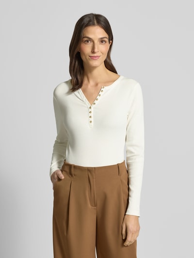 Frauenmodel trägt Slim Fit Longsleeve aus Baumwoll-Mix mit Henley-Ausschnitt von Christian Berg Woman in Creme, feine Textur, kombiniert mit brauner Hose, Rückenlänge bei Größe S 58 cm, Nahaufnahme Oberkörper.