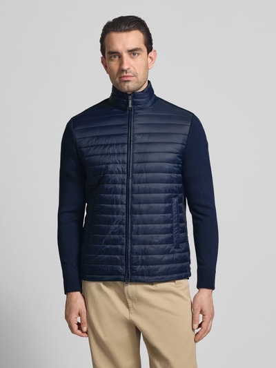 Männermodel trägt Regular Fit Jacke in Stepp-Optik von Colmar Originals, dunkelblau, Stehkragen, Eingrifftaschen, Zweiwege-Reißverschluss, Ganzkörperansicht von vorne. Rückenlänge 67 cm, Schulterbreite 42 cm, Brustweite 51 cm, Ärmellänge 64 cm bei Größe 50.