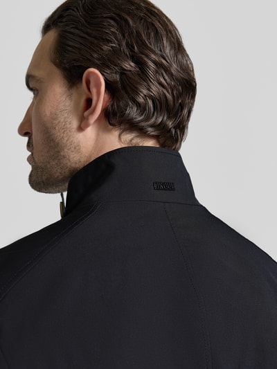 Männermodel trägt Mantel mit durchgehender Knopfleiste von CINQUE mit hohem Stehkragen und Riegel, schwarze Farbe, Detailaufnahme Rückansicht.