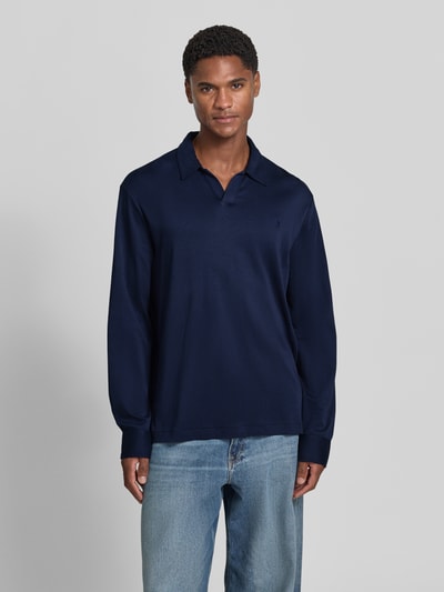 Männermodel trägt Slim Fit Poloshirt aus reiner Baumwolle von Polo Ralph Lauren in Dunkelblau, kombiniert mit Jeans, Ganzkörperansicht von vorne. Herren Poloshirt von Polo Ralph Lauren