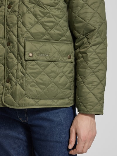Männermodel trägt Regular Fit gewatteerd jack met tweewegritssluiting model 'CITY BEDALE' van Barbour in effen kleuren met satijnstructuur, structuurpatroon, labelopschrift en opgestikte zijzakken, detailaufnahme rechterarm.