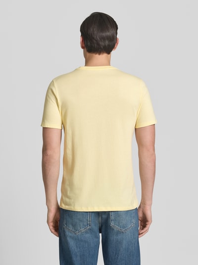 Männermodel trägt T-Shirt mit Rundhalsausschnitt und Label-Stitching von GAP in Hellgelb, reine Baumwolle, Regular Fit, Rückansicht, Ganzkörperansicht.