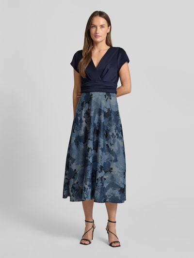 Vrouwenmodel draagt Maxikleid mit floralem Print van Swing, donkerblauw met bloemen, elastische stof, V-hals, taillering, volledige voorkant.