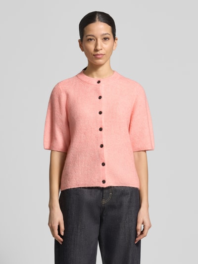 Frauenmodel trägt Strickjacke mit Woll-Anteil Modell 'Jinie Hope' von MSCH Copenhagen in Rosa, Material-Mix, Gerader-Schnitt, Rundhalsausschnitt, Knopfleiste, 1/2-Arm, Rückenlänge 56 cm, Ärmellänge 32 cm, Ganzkörperansicht von vorne.