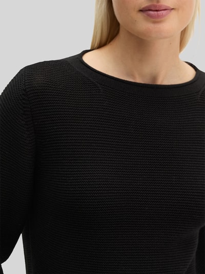 Frauenmodel trägt Regular Fit Pullover aus reiner Baumwolle von MARC O'POLO, unifarben, schwarze Strickoptik, Nahaufnahme Oberkörper.
