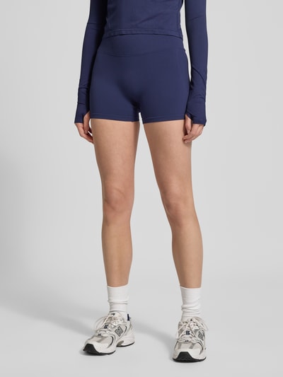 Frauenmodel trägt Slim Fit Shorts mit breitem Bund Modell 'Scrunch' von Fabletics, Elastischer-Material-Mix, Dunkelblau, Ganzkörperansicht von vorne.
