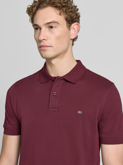 Männermodel trägt Regular Fit Poloshirt mit Stitching von Christian Berg Men aus puur katoen in bordeaux met knoopsluiting, nahaufnahme bovenlichaam.