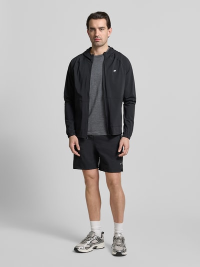 Männermodel trägt Regular Fit T-Shirt mit Rundhalsausschnitt von Fabletics, dunkles Grau, elastischer Baumwoll-Mix, Ganzkörperansicht von vorne.