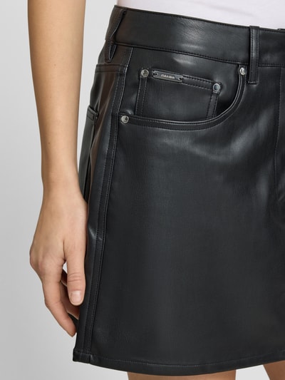 Kobiece modelka nosi Spódnica mini w linii A od Calvin Klein Jeans, imitacja skóry, detal z logo, wpuszczane kieszenie, czarny kolor, detaliczny widok na przód, zbliżenie na dolną część ciała.