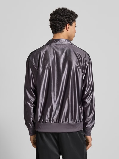 Männermodel trägt Sweatjacke mit Stehkragen von adidas Originals in Metallic-Grau, gerippte Abschlüsse, Rückenansicht, Ganzkörperansicht Rückansicht.