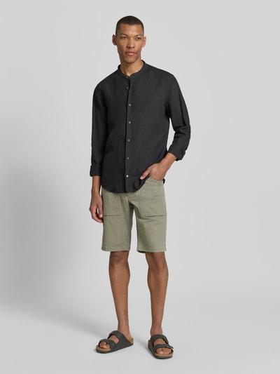 Męski model nosi Regular Fit Cargoshorts aus Baumwoll-Mix od s.Oliver BLACK LABEL, oliwkowy twill, 5 kieszeni, patch z logo; całe ciało z przodu.