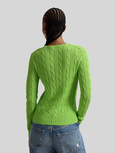 Frauenmodel trägt Strickpullover mit Zopfmuster Modell 'JULIANNA' von Polo Ralph Lauren in leuchtendem Grün, reine Baumwolle, Slim Fit, Rundhalsausschnitt, Label-Stitching, Rückenlänge 58 cm, Ärmellänge 69 cm, kombiniert mit blauen Jeans, Ganzkörperansicht Rückansicht.
