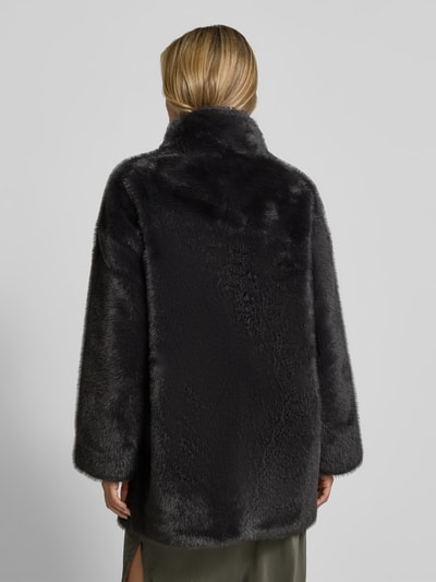 Modelka nosi Wendemantel aus Kunstfell von Juvia, ciemnoszary kolor, prosty krój, stójka, wpuszczane kieszenie, plisa, długość tyłu w rozmiarze S: 80 cm, szerokość w rozmiarze S: 53 cm, długość rękawów w rozmiarze S: 64 cm, widok całej sylwetki z tyłu.