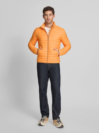 Männermodel trägt Steppjacke mit Zweiwege-Reißverschluss von Colmar Originals in Orange, Regular-Fit, Stehkragen, Eingrifftaschen, Ganzkörperansicht von vorne. Rückenlänge 65 cm, Schulterbreite 47 cm, Brustweite 43 cm, Ärmellänge 67 cm bei Größe 50.