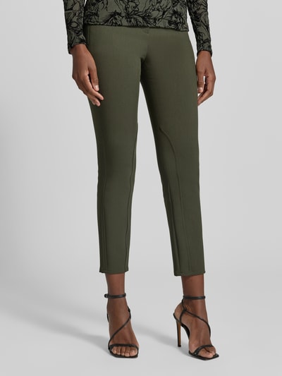 Frauenmodel trägt Slim Fit Schmale Hose mit Viskose-Anteil Modell 'SILEA' von Marc Cain in Olivgrün, Teilungsnähte, Reißverschlusstaschen, Webware, Unifarbe, Mid Waist, Ganzkörperansicht von vorne.