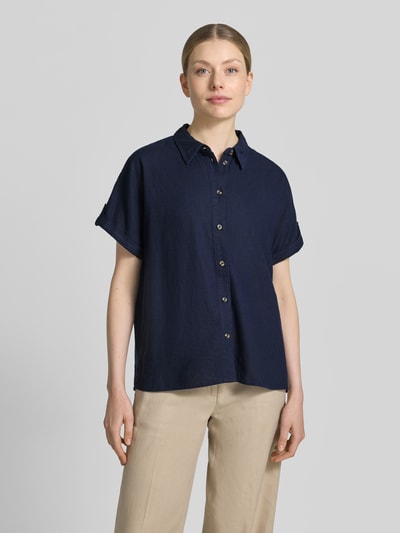 Frauenmodel trägt Relaxed Fit Bluse aus Leinen-Viskose-Mix Modell 'Lava' von FREE/QUENT in Dunkelblau mit Knopfleiste, Hemdblusenkragen, glatte Struktur, Kurzarm, beiger Hose, Ganzkörperansicht von vorne.