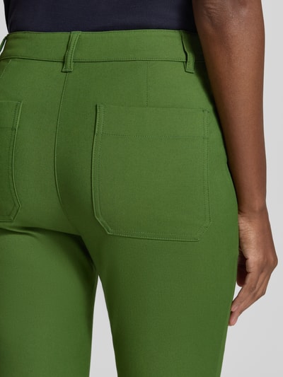 Kobiece modelka nosi zielone spodnie Schmale Hose aus Baumwoll-Mix od Marc Cain, mieszanka bawełny ekologicznej z dodatkiem streczu, krój slim fit, Kieszeń z tyłu, szerokość w rozmiarze 36: 38 cm, długość wewnętrzna nogawki w rozmiarze 36: 71 cm, zapięcie na guzik i zamek błyskawiczny, detailaufnahme.