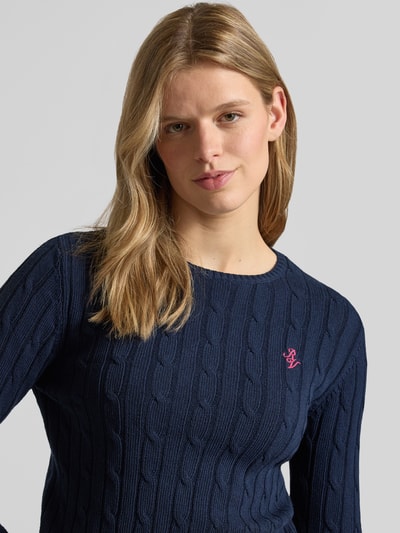 Frauenmodel trägt Strickpullover mit Zopfmuster und Label-Stitching von REVIEW in Dunkelblau, Baumwoll-Mix, Regular-Fit, Nahaufnahme Oberkörper.