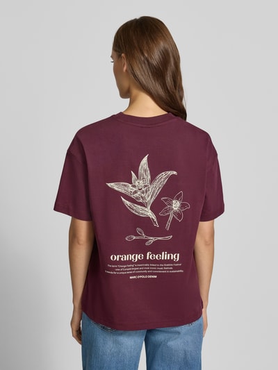 Vrouwenmodel draagt Relaxed Fit T-shirt uit puur katoen van Marc O'Polo DENIM in bessenrood met witte bloemenprint, volledig zicht van achteren.