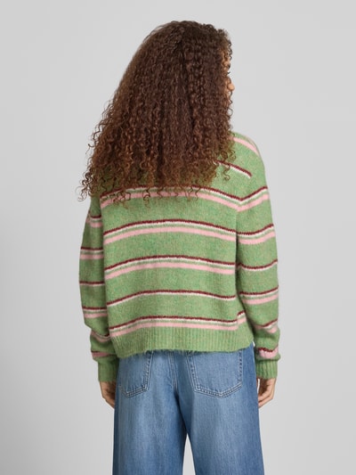 Frauenmodel trägt Cardigan mit Streifenmuster Modell 'CARO' von Topshop, Material-Mix mit Woll-Anteil, Relaxed-Fit, Rückenlänge 56 cm, Ärmellänge 63 cm, grün mit weißen und rosa Streifen, weiche Textur, Ganzkörperansicht Rückansicht.