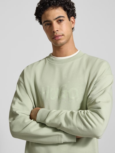 Männermodel trägt Regular Fit Sweatshirt aus reiner Baumwolle Modell 'NIEROFIX_CREW' von Hugo Blue in Unifarben mit Label-Print, Nahaufnahme Oberkörper.