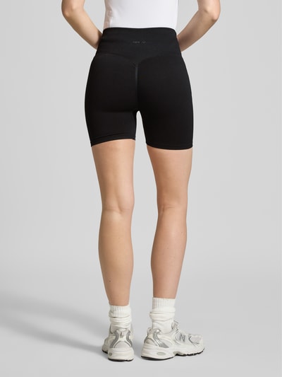 Männermodel trägt czarną Radlerhose mit elastischem Bund Modell 'Shape Seamless' von aim'n, materiał z domieszką stretchu, krój slim fit, Szerokość w rozmiarze S 28 cm, długość nogawki wewnętrznej 11 cm, gładka tekstura, Ganzkörperansicht Rückansicht.