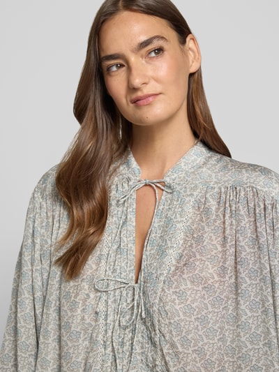 Frauenmodel trägt Relaxed Fit Kurzarmbluse mit Modal-Anteil Modell 'C_BALES' von BOSS Orange, florales Muster in sanften Tönen, Nahaufnahme Oberkörper. Damen Kurzarmbluse von BOSS Orange.
