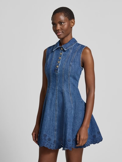 Frauenmodel trägt Minikleid in Denim-Optik von Self-Portrait aus Baumwoll-Mix mit taillierter Passform, Umlegekragen, Ärmelloses-Design, dunkelblaue Farbe, Struktur durch Ziernähte und Lochspitze, Nahaufnahme Oberkörper.