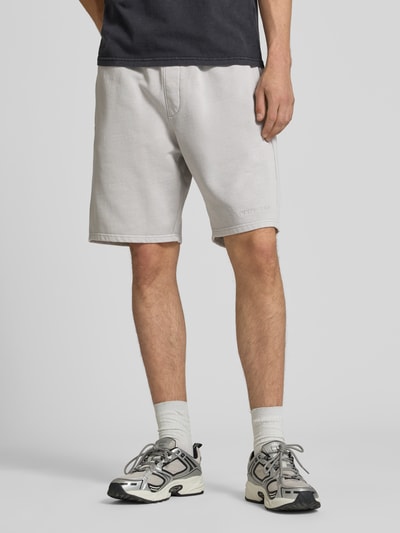 Männermodel trägt Regular Fit Shorts mit Logo-Stitching von Pegador aus Baumwoll-Mix in hellem Grau, Bundweite 42 cm, Nahaufnahme Oberschenkel, Vorderansicht.