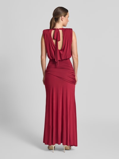 Frauenmodel trägt Abendkleid mit Drapierungen und Wasserfall-Ausschnitt von Lipsy in Rot, figurbetont, Maxilänge, Rückansicht, Ganzkörperansicht. Material-Mix mit Stretch-Anteil, rückseitige Schnürung.
