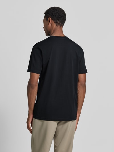 Męski model nosi Regular Fit T-Shirt mit Logo-Stitching von MCNEAL z czarnej bawełny, okrągły dekolt, długość tyłu 70 cm, Ganzkörperansicht Rückansicht.
