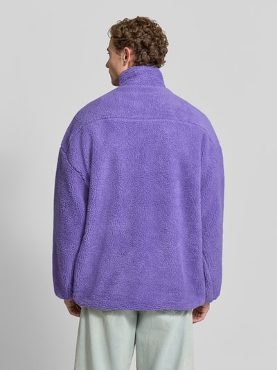 Männermodel trägt Oversized Pullover mit Stehkragen Modell 'HOKTOWN' von American Vintage aus lilafarbenem Kunstfell, Rückenansicht.