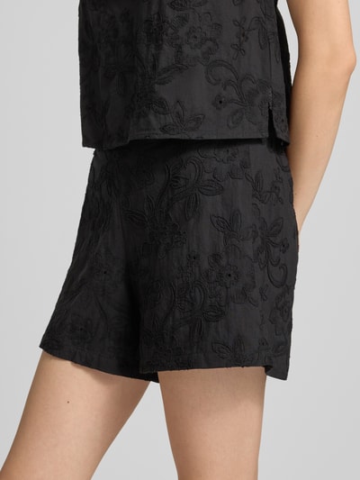 Kobiece modelka nosi Regular Fit Stoffshorts aus reiner Baumwolle Model 'PCGINGER' von PIECES, czarny kolor, tekstura z haftem, zbliżenie na biodra, Damen Stoffshorts von PIECES.