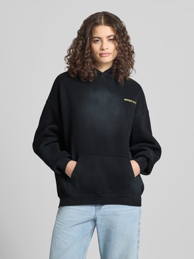 Frauenmodel trägt Hoodie mit Logo-Stitching von ANOTHER COTTON LAB, mieszanka bawełny, luźny krój, kaptur, kieszeń kangurka, Ganzkörperansicht z przodu