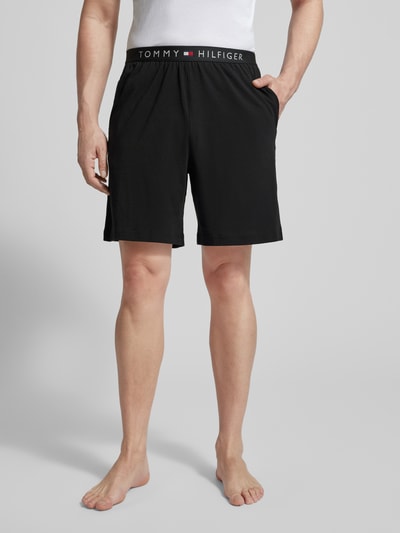 Männermodel trägt schwarze Regular Fit Sweatshorts aus Baumwoll-Mix von Tommy Hilfiger mit elastischem Bund und Logo, Ganzkörperansicht von vorne.