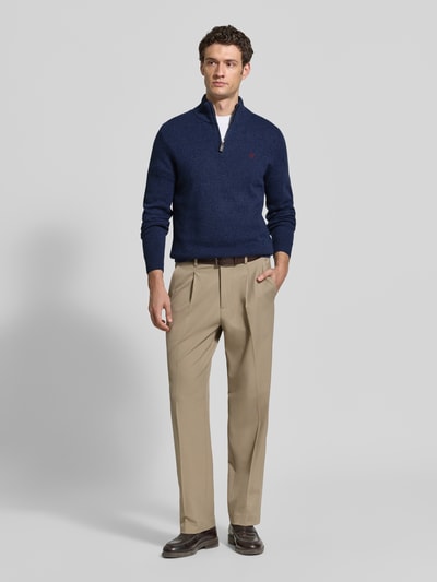 Männermodel trägt Regular Fit Strickpullover aus reiner Wolle von MCNEAL in Dunkelblau mit Troyer-Kragen und Logo-Stickerei, Ganzkörperansicht von vorne.