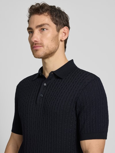 Männermodel trägt Regular Fit Poloshirt aus reiner Baumwolle Modell 'ADRIAN-CA' von Strellson, dzianina w warkocze, imitacja dzianiny, krój regular fit, kołnierzyk polo, dekolt w serek, listwa guzikowa, krótki rękaw, kolor ciemnogranatowy, materiał: bawełna, Nahaufnahme Oberkörper.