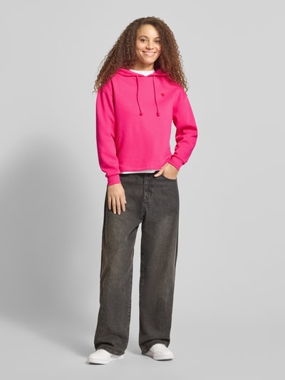 Frauenmodel trägt Regular Fit Hoodie aus Baumwoll-Mix Modell 'CHILLI' von Pieces, Optik: Unifarben, Farbe Pink, Stickerei, Kapuze mit Tunnelzug, Langarm mit geripptem Ärmelabschluss, Sweat-Material, Ganzkörperansicht von vorne.