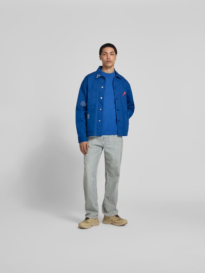 Männermodel trägt Hemdjacke mit Motiv-Stitching von Forét in Blau, Baumwoll-Mix, Relaxed-Fit, AufgesetzteTaschen, Ganzkörperansicht von vorne. Rückenlänge bei Größe M 73 cm.