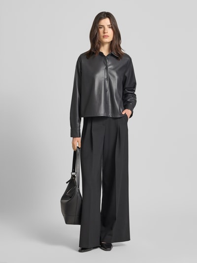 Modelka kobieca ma na sobie Relaxed Fit Hemdjacke in Leder-Optik Modell 'Zeather' od Someday, czarny materiał skóropodobny, wykładany kołnierz, listwa guzikowa, długość tyłu w rozmiarze 36: 52 cm, szerokość ramion w rozmiarze 36: 40 cm, szerokość klatki piersiowej w rozmiarze 36: 65 cm, długość rękawów w rozmiarze 36: 63 cm; widok całej sylwetki z przodu.
